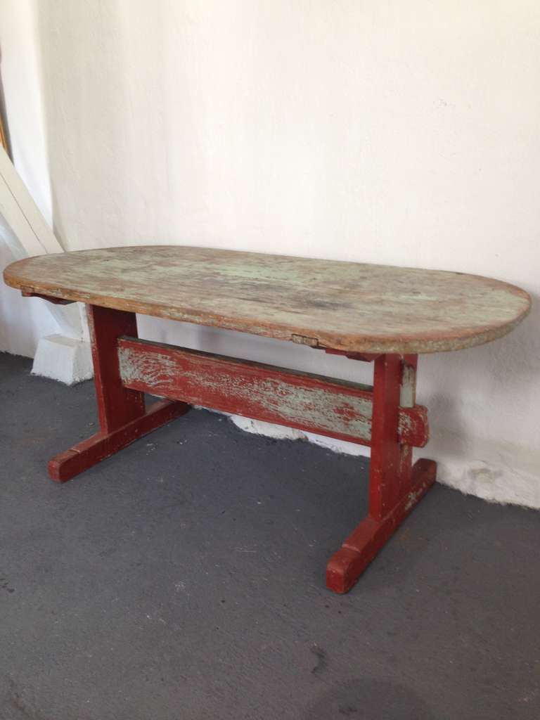 Swedish trestle table made late 18th Century or Early 19th Century. Oval top.  Pine wood with original paint in a mint green coming through the red paint.