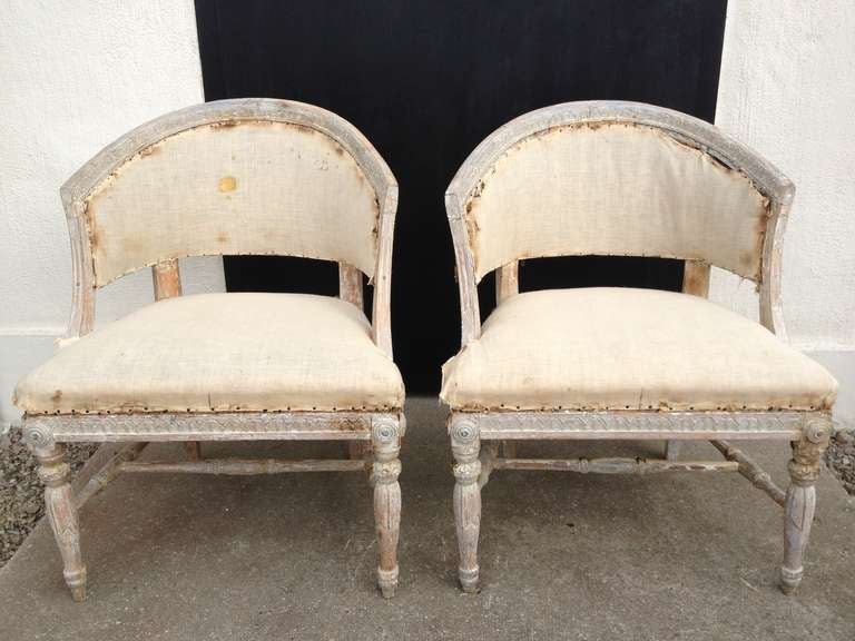 A pair of barrel back chairs in ALL original. Stripped to their original paint. Curved backs with leaf tip carvings symmetrical to the carvings on the frieze. Turned foot cross connecting the rounded legs with leaf decor. Circular corner decorations.
