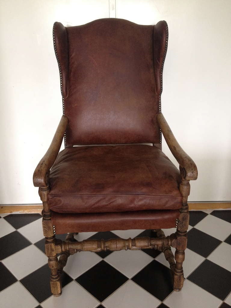 A Swedish Baroque period wingback chair. Made ca 1690-1730 during the Carolean part of the Baroque period. Made of oak and upholstered in vintage dark brown leather. All original finish.