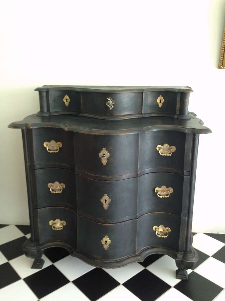 An absolutely amazing black painted chest of drawers from the Baroque period. Beautifully curved front and carvings. Brass hardware.