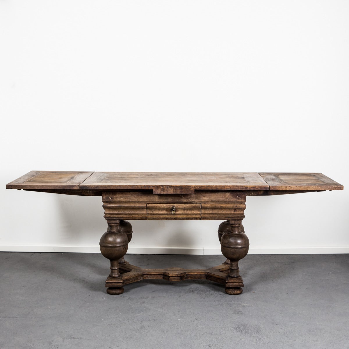 A extendable dining table made in Sweden during the Baroque period circa 1700. Restored. Made from oak with baluster shaped legs connected with a diagonal foot cross. Standing on ball feet. Drawer in frieze. Two pull out leaves on each short end -