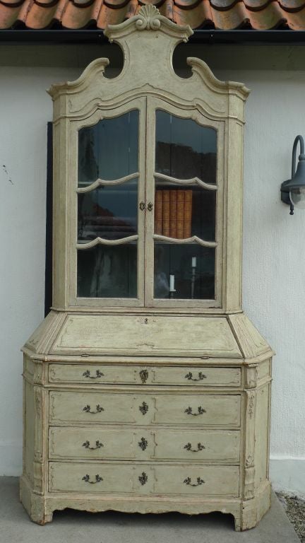 An Italian slant front desk with bookcase -the slant front writing desk opening to a blue interior. The entire piece is decorated with curves and rocaille. Hardware and key plates are all made in bronze. Closed depth 23.5