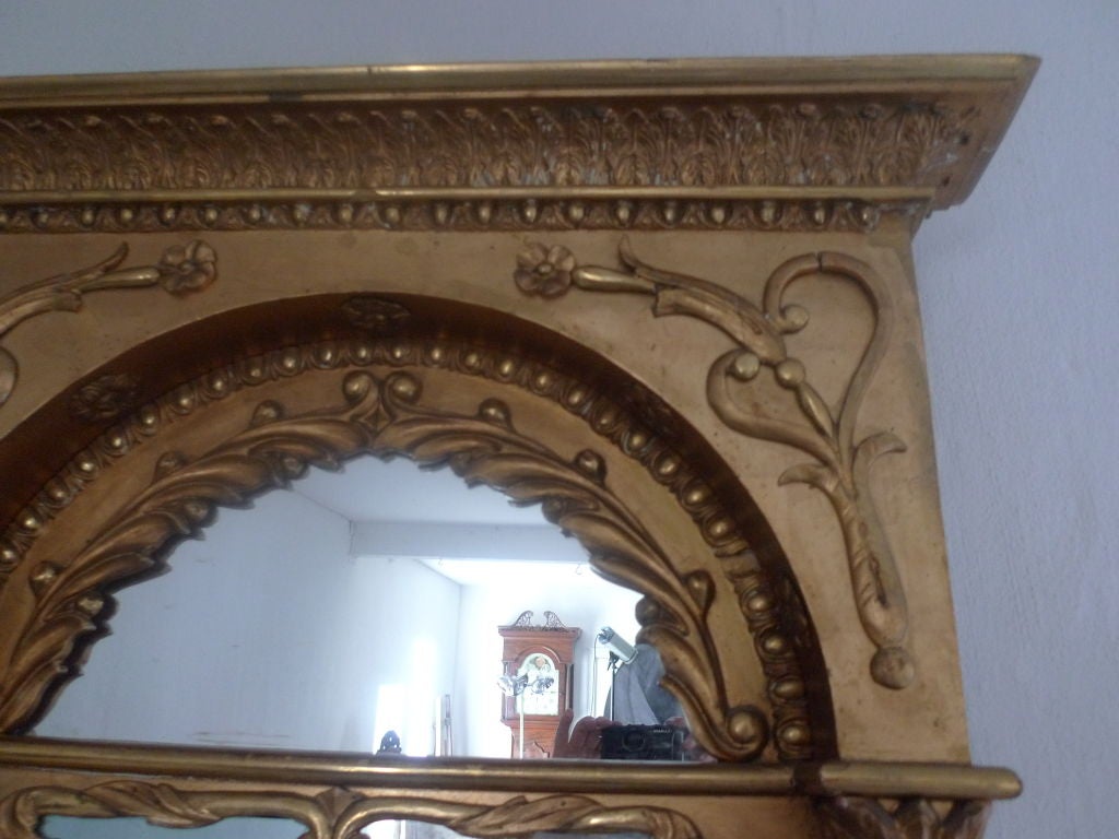 A beautiful and large Swedish Karl Johan mirror from the early 19th century. Its made in gilt wood and decorated with a carved corniche with a demi lune shaped top mirror. One colon on each side according to the symbols of the neoclassisism.