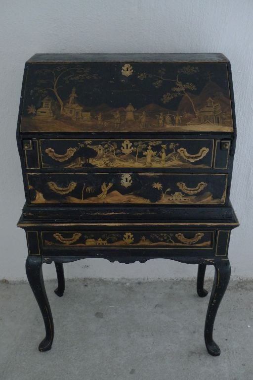 A beautiful black lacquered secretary with gilt paint decorative paintings. Made in 2 parts. Has a highly decorated interior. Standing on Rococo shaped legs. Depth with desk open: 21.5 in