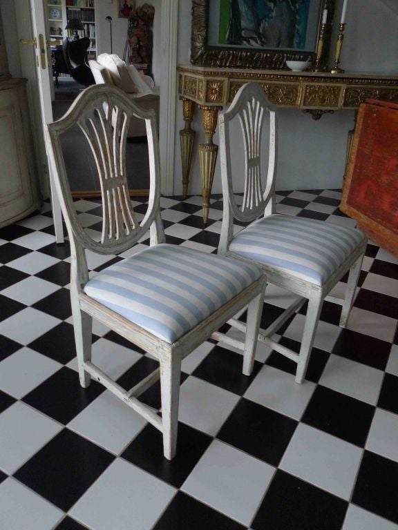 A pair of high quality side chairs with a shield shaped, Hepplewhite inspired back splat. Tapered legs with a foot cross.