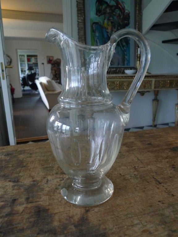 A beautiful Swedish glass carafe. Helmet shaped body with olive edged decorations and a s shaped handle. Round foot with olive edging .