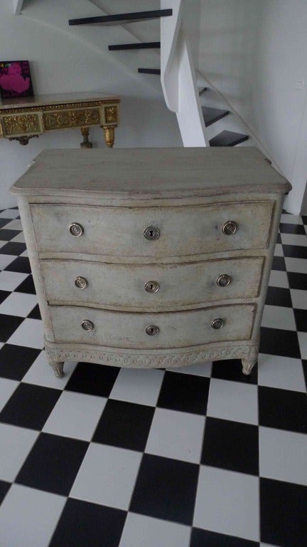A beautiful light gray painted chest of drawers with carvings on base. Channeled legs and a curved front.