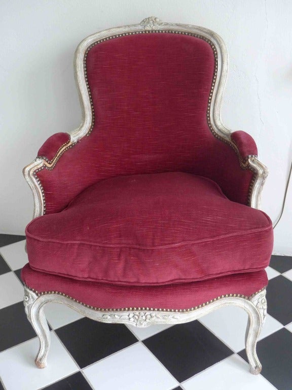A lovely bergere made during the 19th Century in France. Upholstered in a red velvet. Additional dimensions: Seat Depth: 18.5 in, Depth of lower part of chair: 21.5.