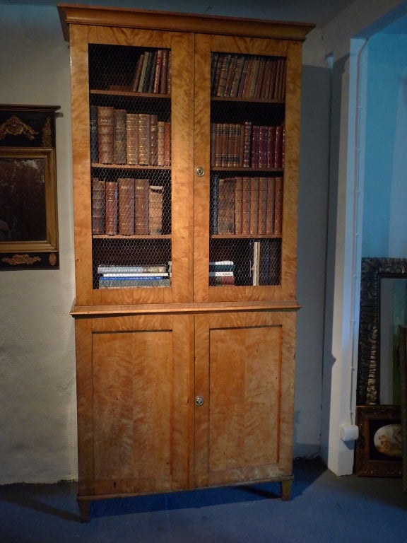 A great bookcase with open doors covered by chicken wire on a closed base with tapered legs. Shelving interior