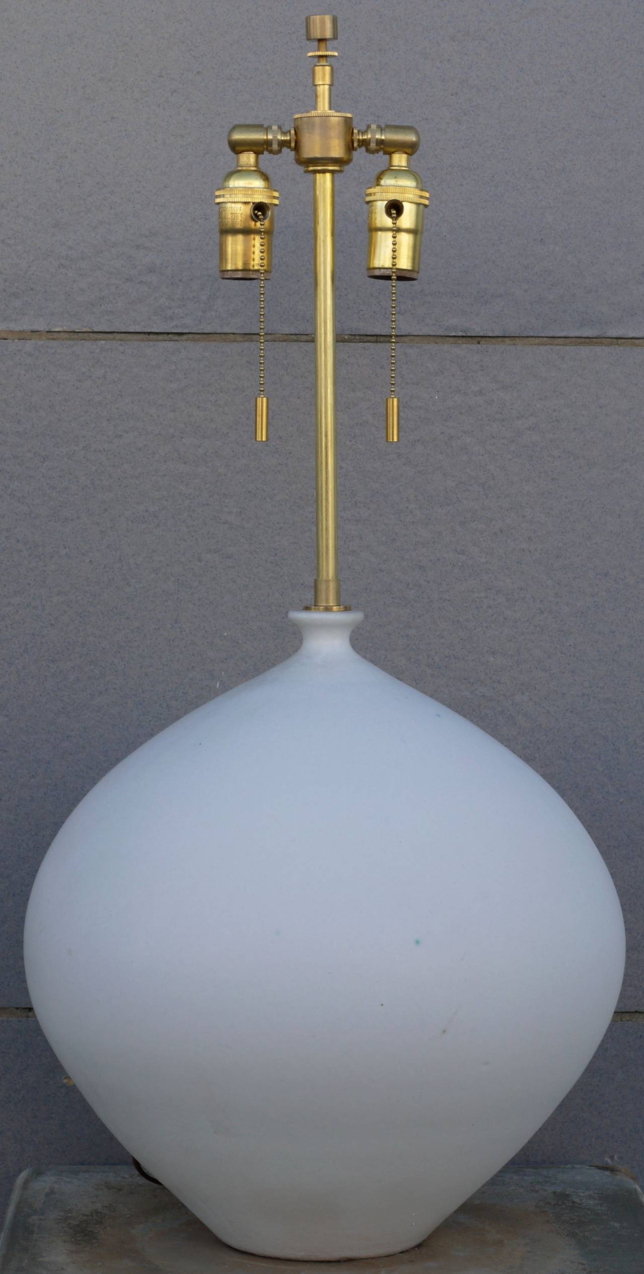 Wonderful magnesium white glazed lamp by Design Technics. This design is a rare one as usually this shape had a footed base. It is signed with impressed mark on back above plug. White glaze with an occasional blue spot.