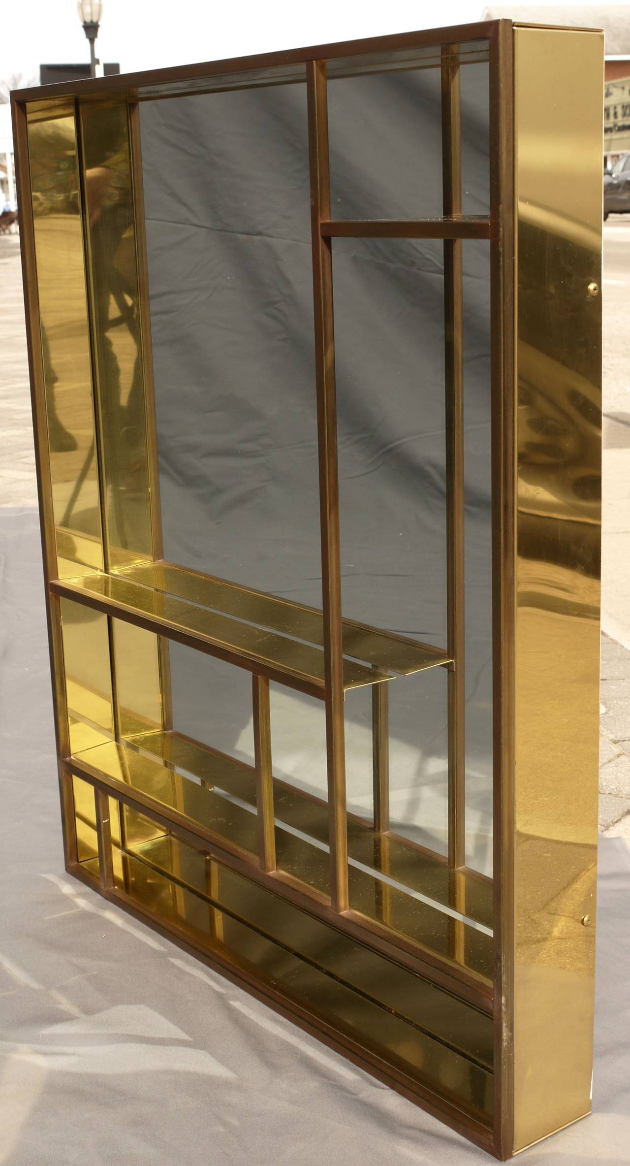 Architectural brass mirror or hanging curio shelf by Curtis Jere. Signed and dated 1979 on the right side vertical. This piece has a wonderful architectural form and the brass reflective accents only add to it's mondrian like appeal to the design.