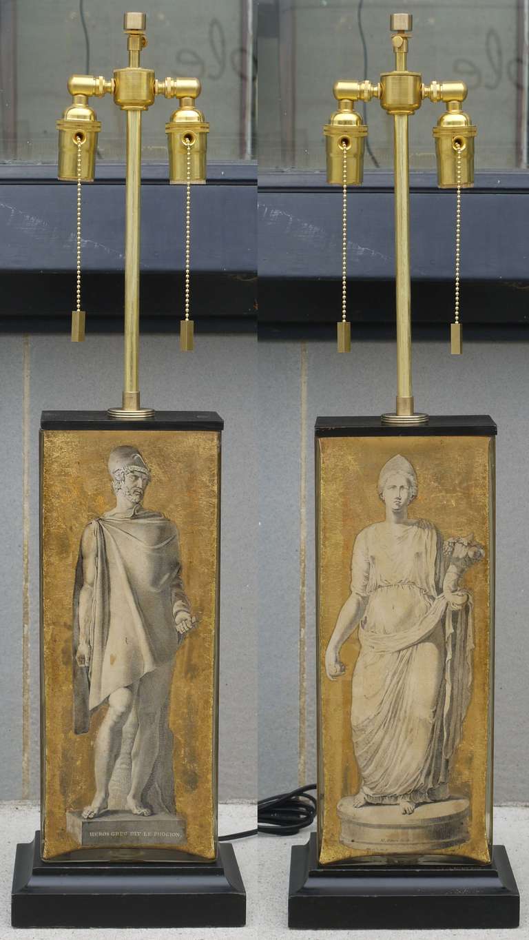Stunning pair of neoclassical eglomise lamps featuring 19th century engravings of Roman figures which have been surrounded by gold leaf finished with a lacquered base and lid.