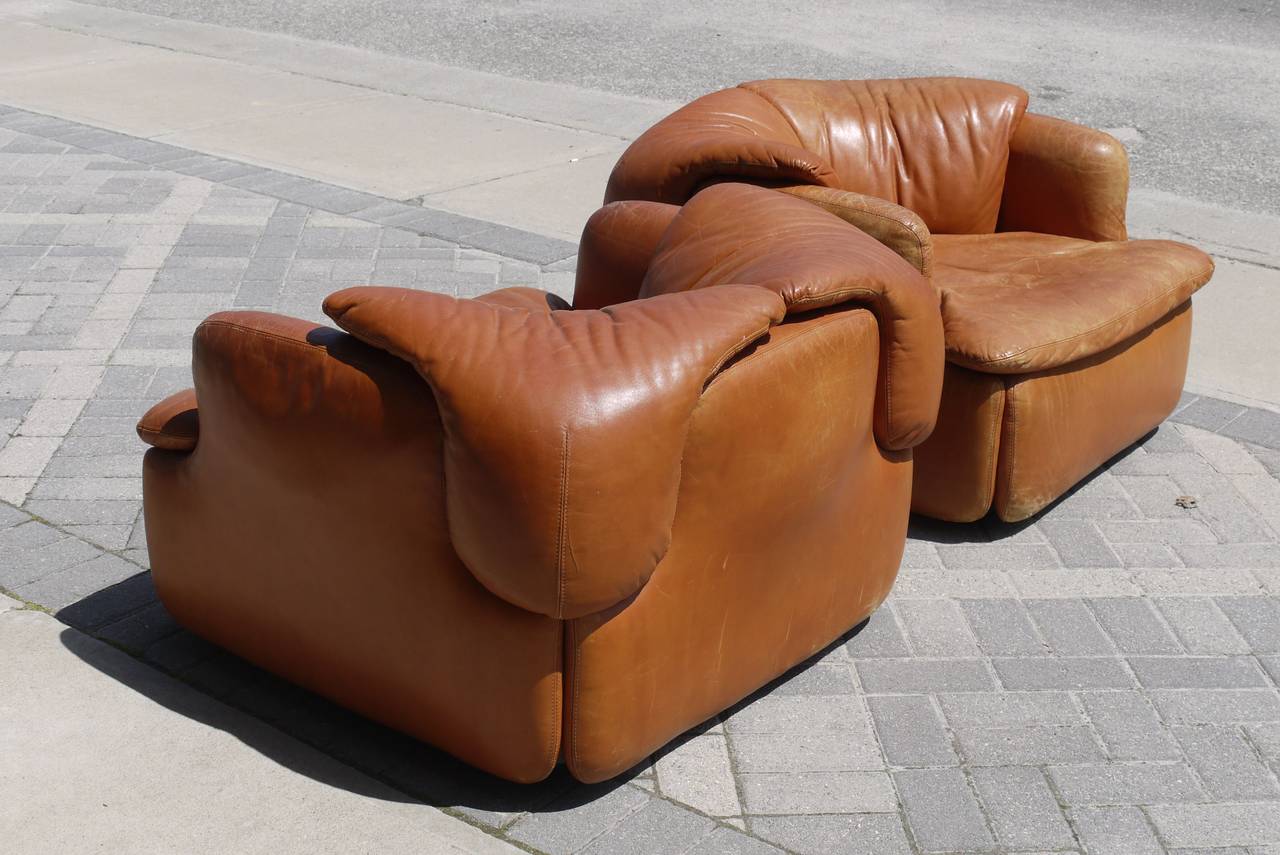 Stunning pair of cognac leather 'Confidential' club chairs by Alberto Rosselli for Saporiti. Upholstered over a metal frame and seated on a fiberglass base signed Saporiti. We also have the matching sofa available. Alberto Rosselli was most