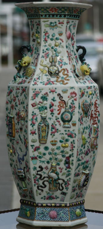 A Large 19th Century hexagonal baluster form vase with double handles moulded to represent gnarled branches with twin fruiting pomegranates.  The central part of the vase is decorated high relief with scholars objects, including censers, bottle