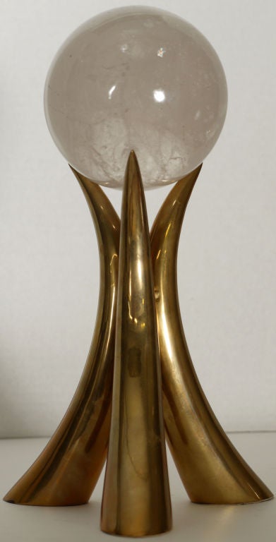 Stylish 1970's tusk shaped brass stand with a 4.5 inch rock crystal sphere resting on the top.