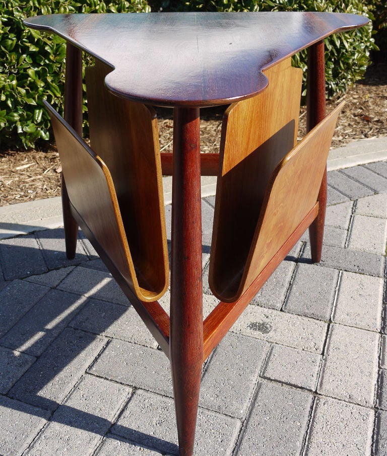 A triangular table in solid walnut with two bent ply magazine holders designed by Edward Wormley for Dunbar with early metal label.  Has an early sap walnut top.