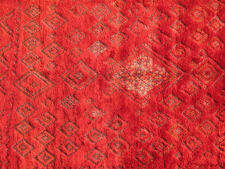 Fabriqué dans les hautes montagnes de l'Atlas, ce magnifique tapis marocain vintage du milieu du siècle dernier, datant des années 1950, présente un motif de losanges et de zigzags sur toute sa surface. La laine en peluche a été teinte d'un rouge