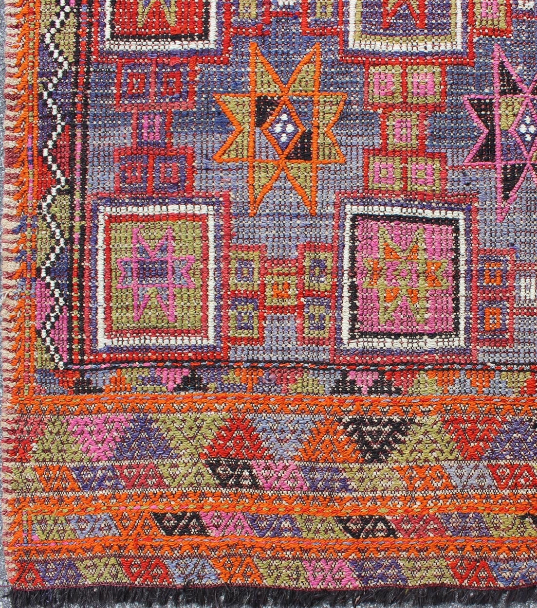 Rendu en forme d'étoile avec un assortiment d'éléments géométriques tachetés et mouchetés, ce Jajeem/Jijim/Kilim unique du milieu du siècle présente un éventail de tons riches et colorés avec du bleu, du violet, du vert, du jaune, de l'orange, du