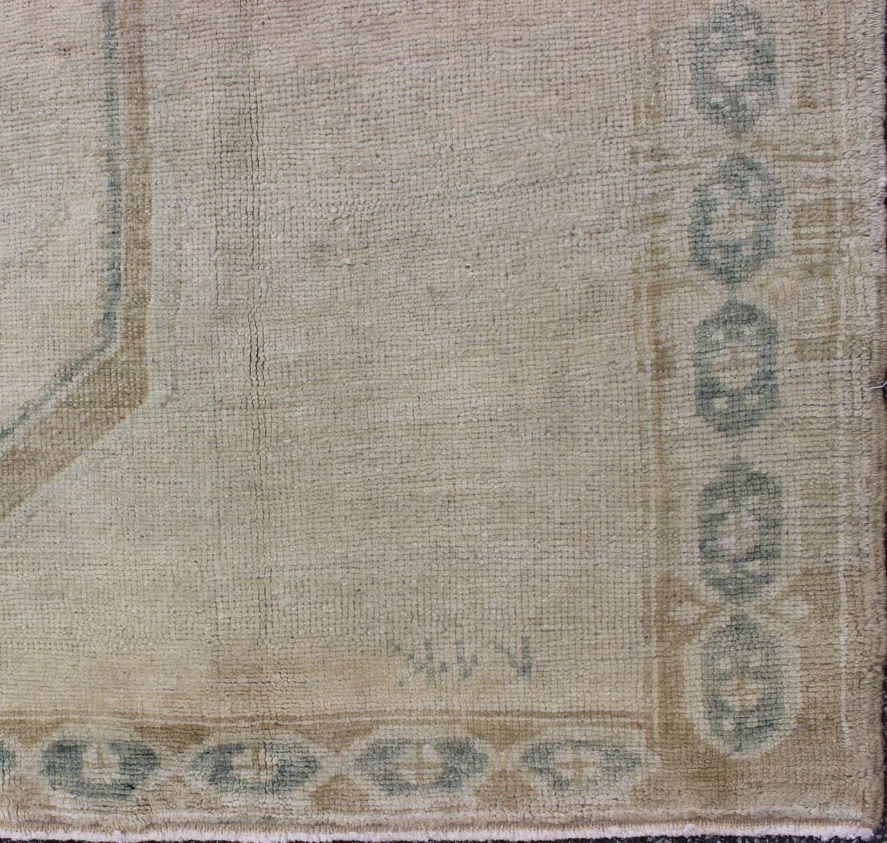 This vintage Oushak features medallions with the simplicity of a tribal design and elegance of a soft color pallet. The light blue border is characterized by a repeating chain design.
Measures: 4'7 x 10'1.