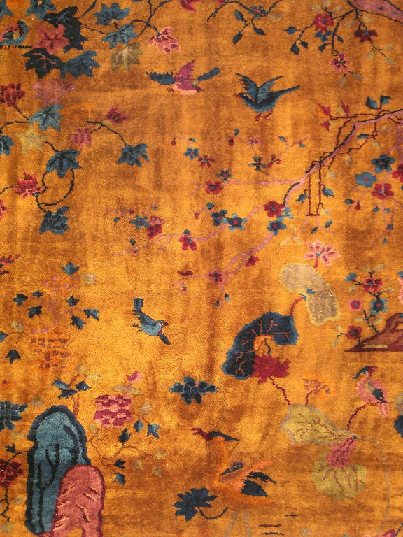 This antique Chinese rug from the turn of the early 20 Century displays a gorgeous array of garden life.  Beautiful birds take flight across the field of gold as flower petals float, branches stretch and rocks take hold.  This rug comes to life in a