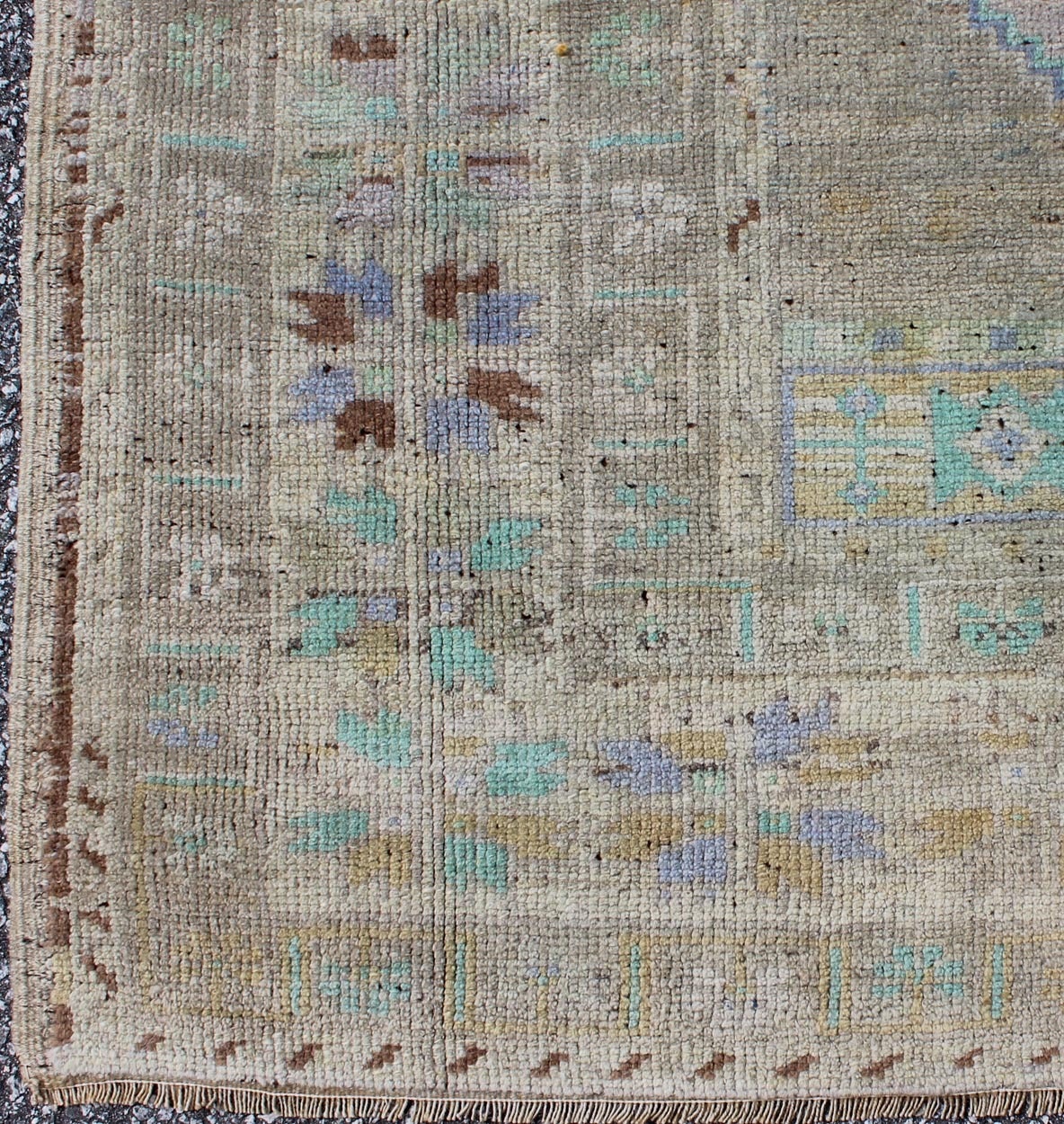 This light colored Oushak demonstrates a variety of delicate colors upon an elegant design. The multi-shaded colors of lavender, taupe, green, blue, purple, ivory and gold  spreads throughout  the rug creating an beautiful art for the floor.