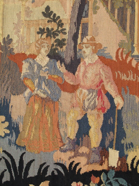 Measures: 4' x 5'5.
This beautiful French tapestry was crafted around the turn of the 20th Century and features a pictorial design depicting two individuals frolicking in nature with a large garden in the background. The piece is resplendent in a