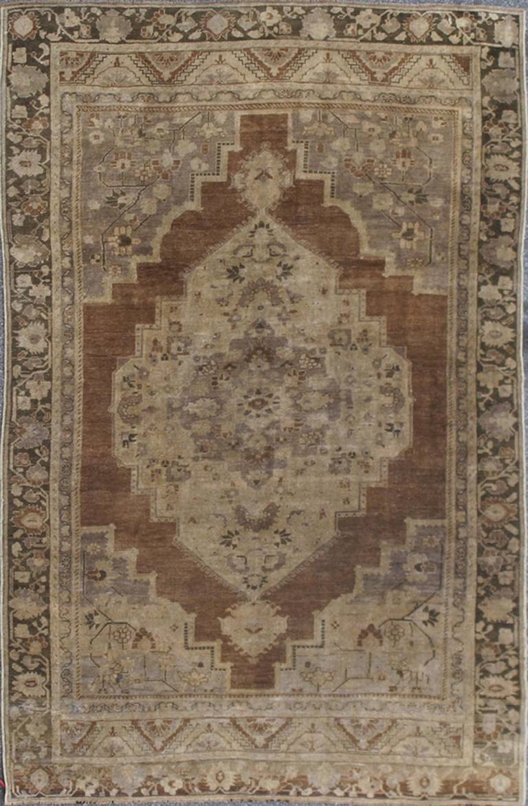 This magnificent Oushak beautifully illustrates the impressive craftsmanship of the Turkish weavers. The striking design shows a large medallion flowing through the rugs' center field of brown, gray and tan colors. A multi-tiered border frames the