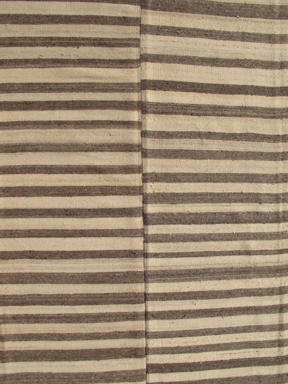 This Vintage Turkish Kilim from the 1960’s is composed of two Grey and Bone Colored Striped Panels joined to form a perfect room sized Carpet with reversible capabilities.
