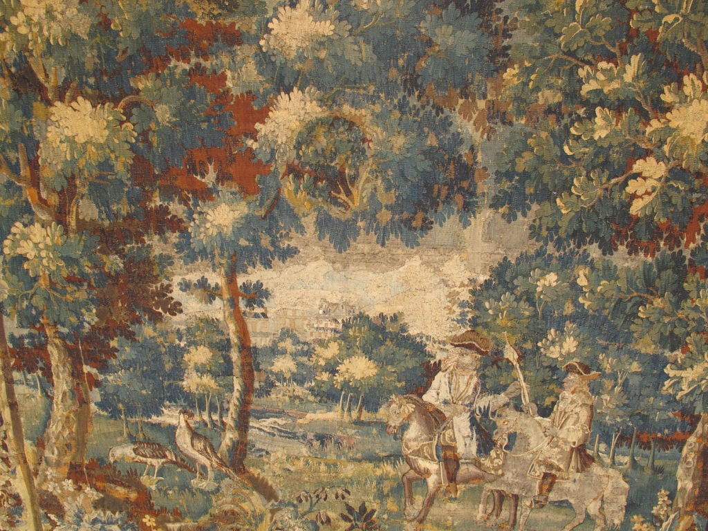 This spectacular Antique Tapestry was beautifully woven by the skilled Flemish artisans of the early seventeenth century.  The central field is presented with a lush Arcadian landscape filled with the deep green and umber tones of abundant foliage.