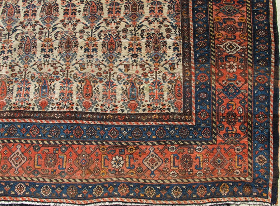 This antique Persian Bidjar has a delightful ivory background, with a repeat boteh pattern. The border has great medium blues, coral and natural brown. The colors in this rug are light and medium blue, ivory, coral, earth tones and browns. 12' x