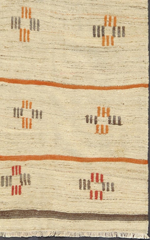 Set on cream color background, this beautiful Kilim displays a random and spaced out lines in red, orange and gray. 5'10 x 9'11.