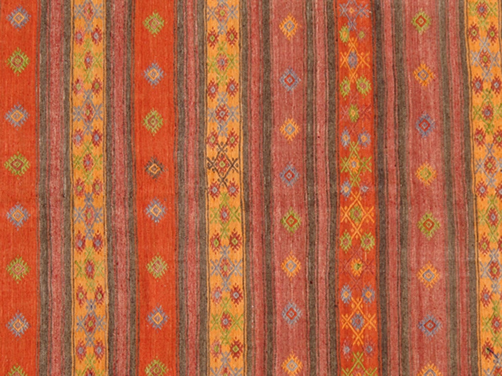The brilliant Kilim displays orange-red, yellow, maroon-red and dark gray stripes. The embroideries and details include yellow, yellow green, orange and light blue. 6'4 X 11'5.