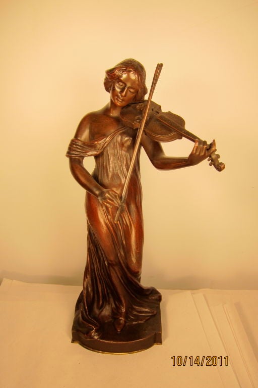 Vintage late 19th century bronze sculpture by German artist M. Fahnrichog. The sculpture portrays a young female musician playing the viola. The female subject is<br />
dressed in a flowing gown that accentuates her form & romances the mood. The