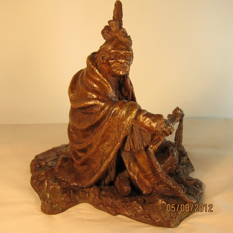 This is a small bronze sculpture of an American Indian seated on the ground with a blanket wrapped around him. The Indian is holding a peace pipe supportive of the non violent state that Kauba is portraying. The bronze is highly detailed & bears a