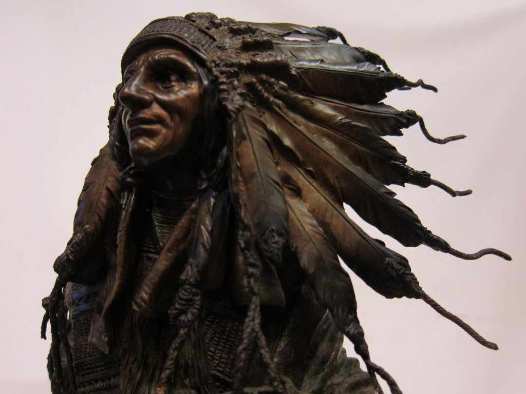 A superbly detail;ed patinated bronze sculpture signed by Carl Kauba.This American Indian chief is elaborately costumed complete with traditional feathered headdress, chieftain's shield & tomahawk mallet. Kauba's sculpture captures the essence of