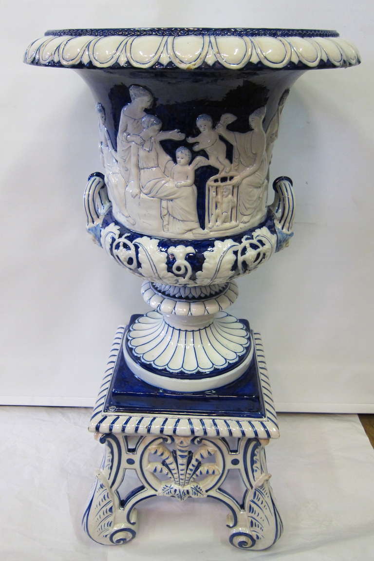 An early 20th century continental palace size terra cotta planter is designed in a rich high glaze cobalt & white finish.
The body of this vintage piece features decorative applied handles that accent a relief of women that encircle the piece. This