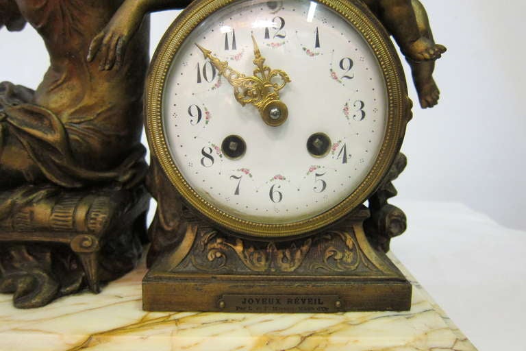 This early 20th century vintage timepiece has a French bell movement & is decorated with a mythical seated deity admiring herself in a mirror held by cupid. The figures & clock are mounted on a veined white marble base. 
The specter clock housing &