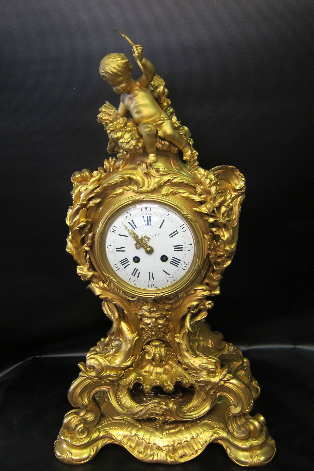 This impressive example of an early 20th century French Rococo palace size clock set is designed by the prestigious E. Collin & Cie of Paris. The sculpted ensemble is detailed with crisp elaborate scrolling that is accented with a full figure cupid