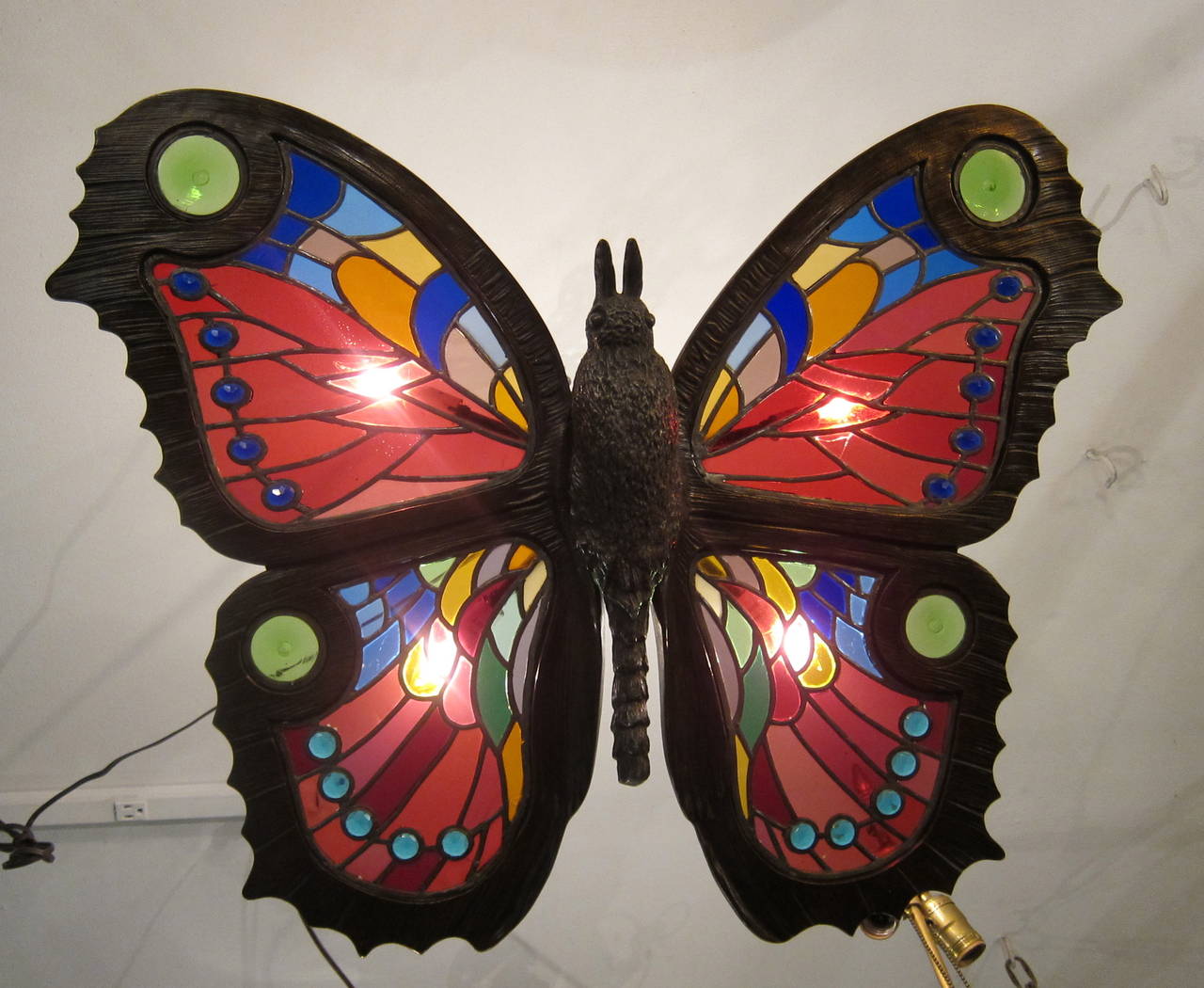 This wonderful, large butterfly fixture has intricate stained and jeweled glass panels within the sculptured bronze framework of its wings. The bronze body
of the butterfly is well defined and artistically rendered. The reverse of the body displays
