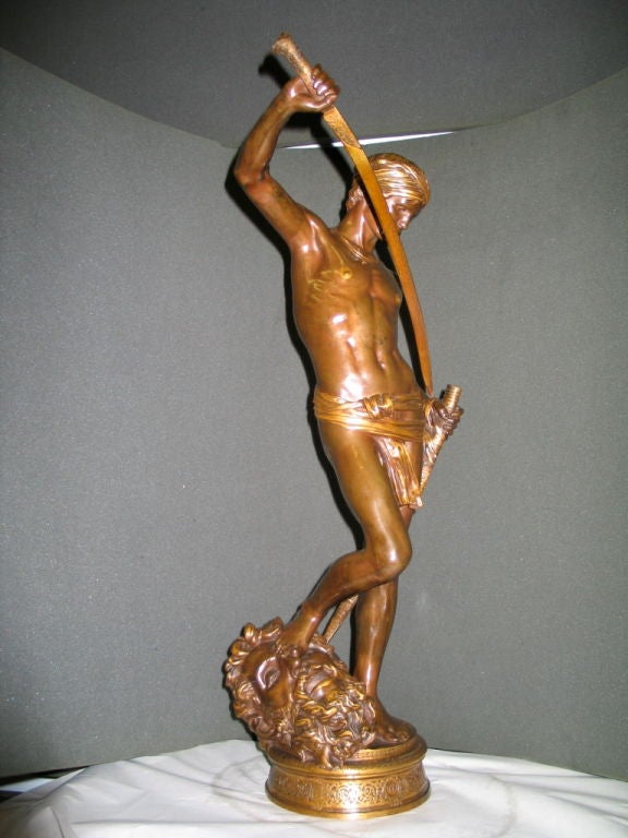 A detailed sculpture of the young David returning his sword to its sheath after his legendary defeat and beheading of Goliath. David is posed, proudly victorious, with one foot resting upon his fallen victim's head.  The bronze has a wonderful