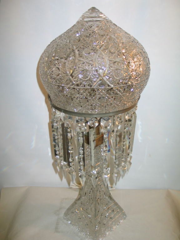 This dramatic cut glass lamp is a superb example of the superior quality of American

cut glass manufacturers during the early part of the 20th century. A pristine crown dome glistens with intricate geometric designs that are wonderfully weaved