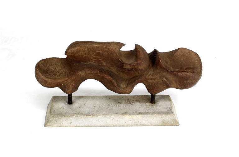 Large carved wood abstract sculpture on cement base.