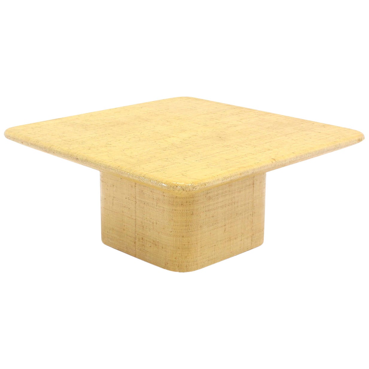 Table basse carrée recouverte de tissu sous bord biseauté.