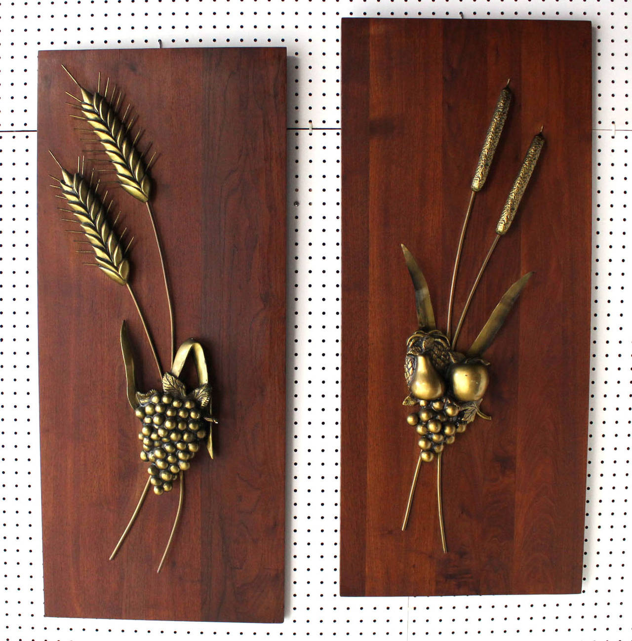Pair of solid cast metal sculptures of wheat, grapes, apple, pear and reed on solid walnut board.