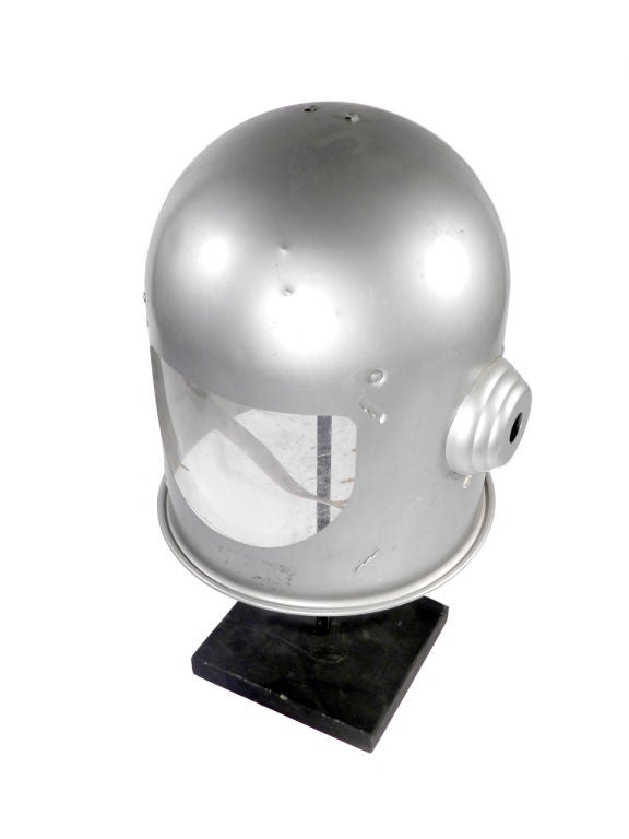This is a 1960's style toy space helmet. It has the original paint, plastic shield and interior head straps. On the display stand it stands 16.5 inches tall. There are a few small dents here and there but no rust and shiny paint.