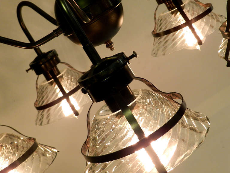 This is a unique chandelier using 1920s industrial snap-in shades. I believe these were made by the X-Ray Lamp Company. They have an elegant and complex industrial look. Each shade haa a 6.6 inch diameter and takes a standard size brass socket. This