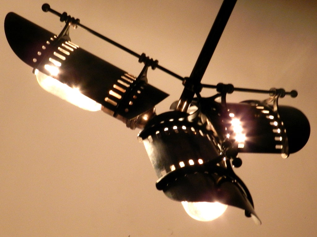 Inspired by early vented industrial shades. This complex pendent has a 16 inch diameter. The softly curving shade has industrial cutouts that cast subtle patterns of light and shield the three tubular bulbs. Early French railroad station roof
