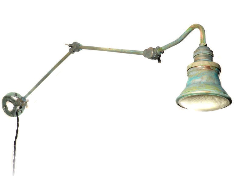 This brass and copper lamp is articulated at 3 points and extends three foot from the wall. The interior of the spots are silvered and a brass ring holds a textured 3.75 inch glass lens.
We have a number of these in stock. This shade and glass lens