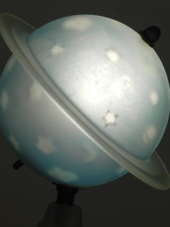 This blue frosted glass Saturn lamp is an exquisite and unusual example of Art Deco style made to commemorate the space theme of the 1939 New York World's Fair. The shade is made up of 2 pieces held together by a metal axis. The lamp is in very good