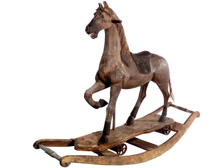 Thisis a nice early well carved example with good proportions, and an active raised leg stance. There is still original paint, detailed leather saddle, glass eyes and real horse hair tail.
One of the cast iron wheels is missing.
For questions or